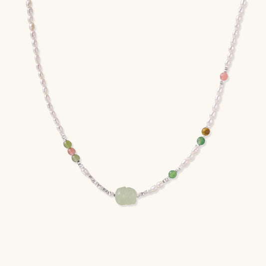 Delicate pearl necklace with pale green serpentine jade centerpiece and colorful agate beads on cream background